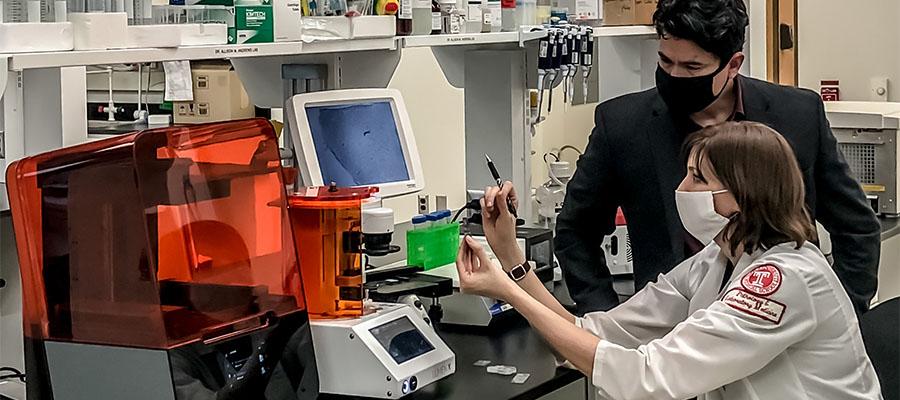 Drs. Servio H. Ramirez and Allison M. Andrews examining a novel microfluidic device in lab