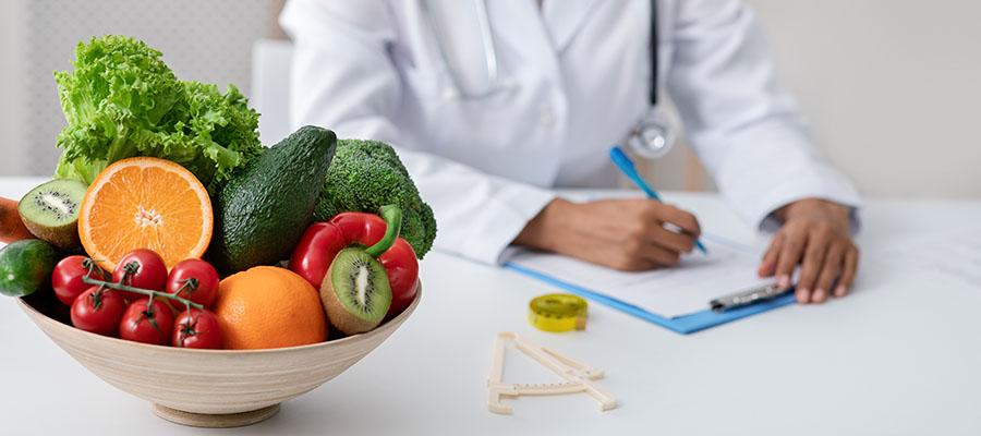 Doctor writing notes next to bowl of fruit