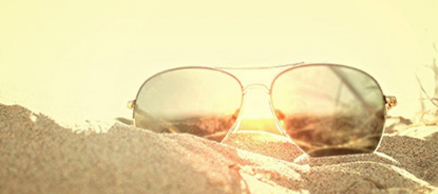 Pair of sunglasses laying on top of sand