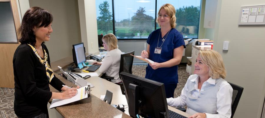 Receptionist assists patient at the front desk of Temple Health Oaks