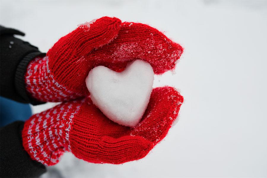Heart-shaped snowball in gloved hand