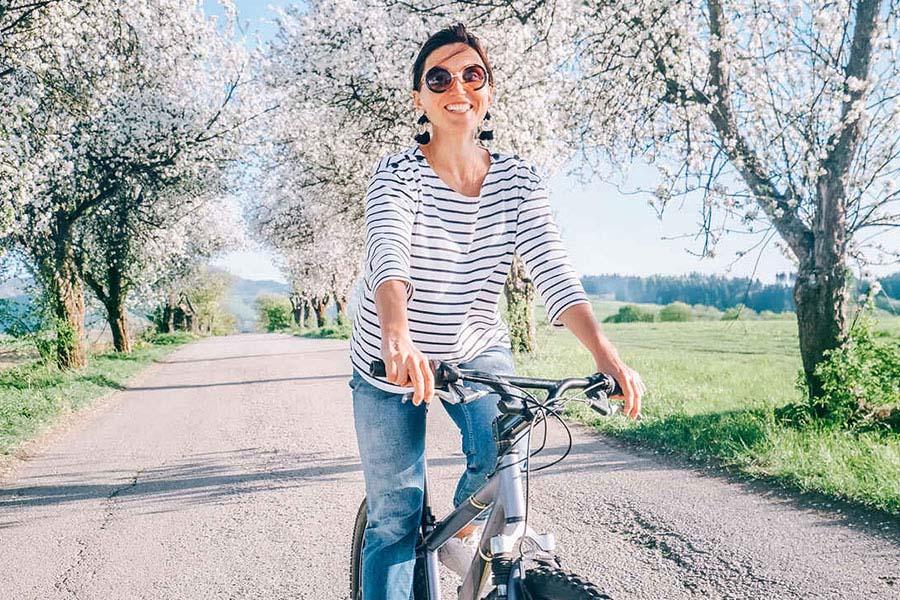 Woman riding her bike through a path with blooming trees