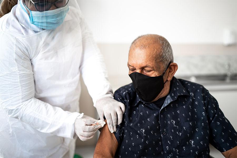 A doctor giving senior Hispanic man the COVID vaccine