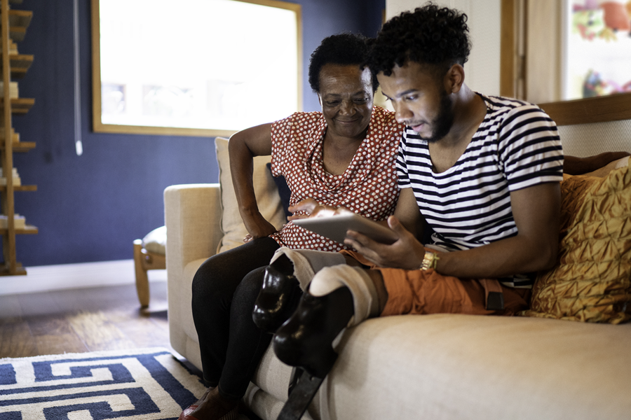 grandson-grandmother-review-information-on-tablet-sitting-on-couch