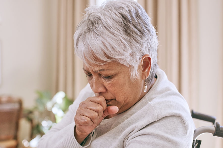 Older woman coughing into hand