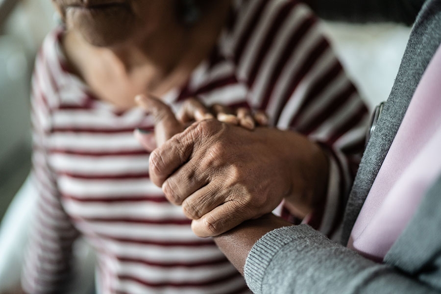 Caretaker holding patients hand