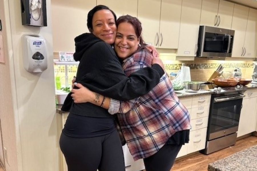 Indira Kwaadu (left) and Krystal Cartagena (right) share a hug while volunteering.