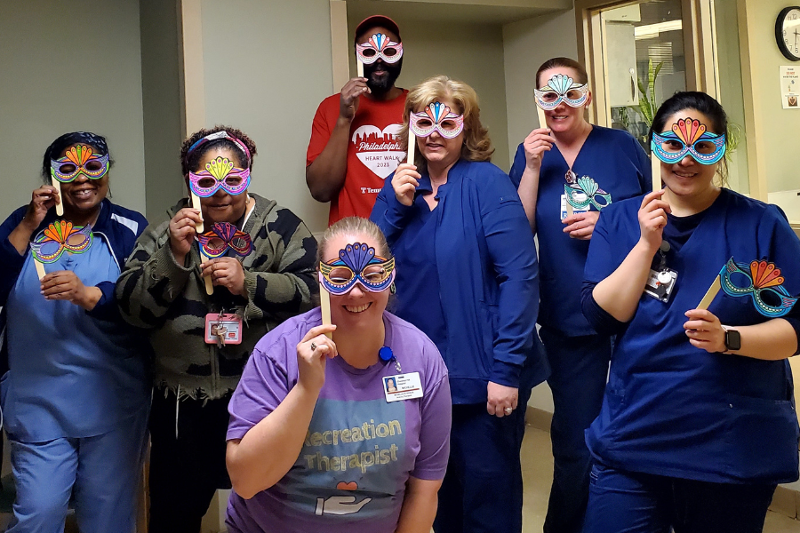 Temple Health-Chestnut Hill Hospital team members (with Peterson at center) show off their Mardi Gras masks.