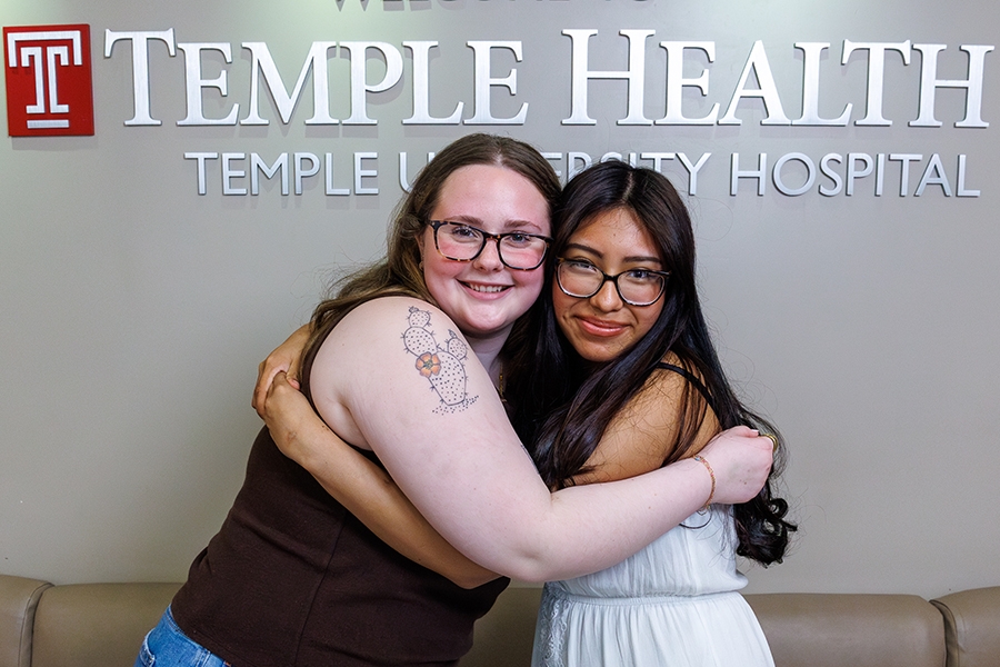 Megan and Evelyn hugging in front of Temple Health sign
