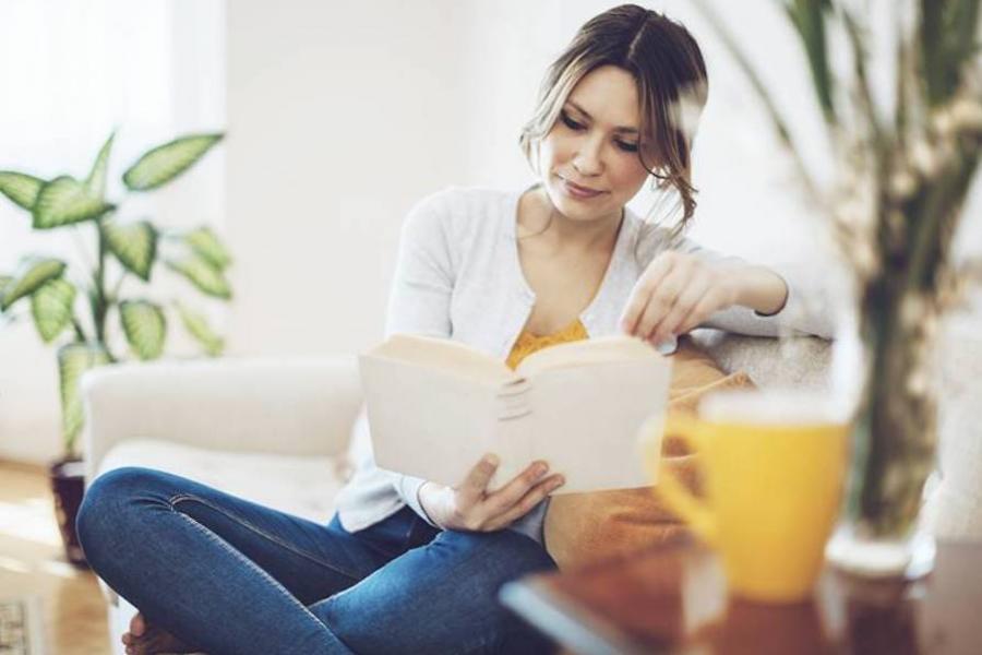 Woman reading a book on the couch in her living room
