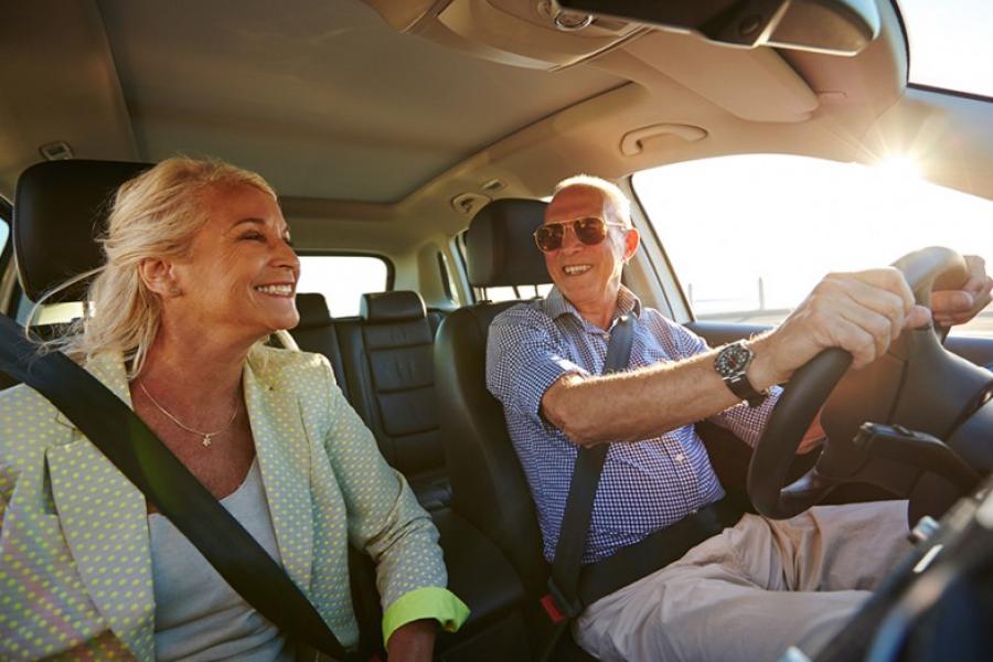 Husband and wife smiling while driving in car