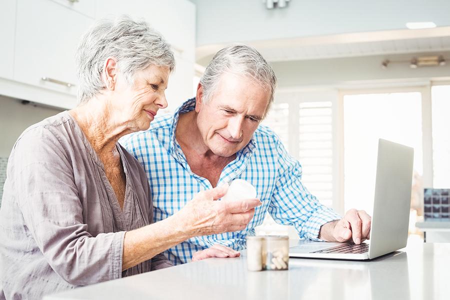 Older couple going over medications together at kitchen counter