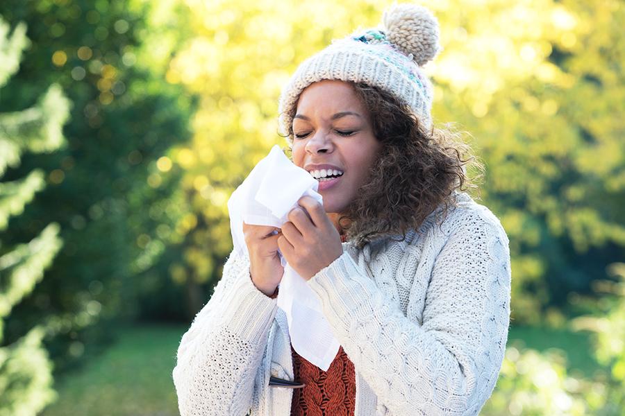 Woman sneezing from allergies outside