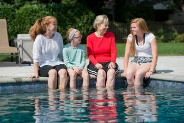 Temple patient Betsy and her family sitting with their feet in the pool
