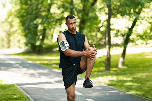 Black athlete stretching leg after sports injury