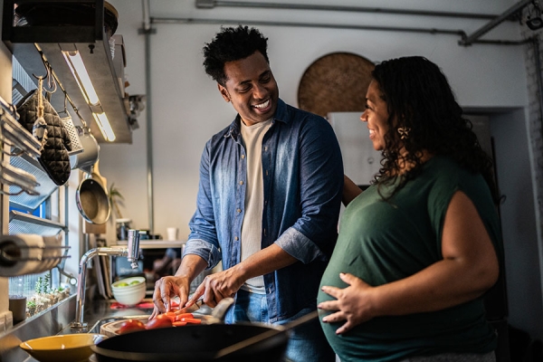 Pregnant woman cooking in kitchen with husband