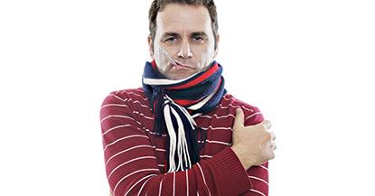 Man wrapped up in a scarf with a thermometer hanging out of his mouth